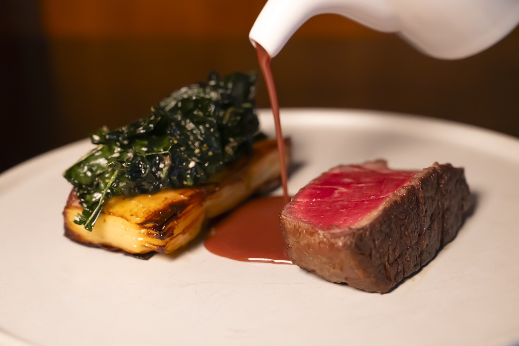 Chef finishing a plated steak dish